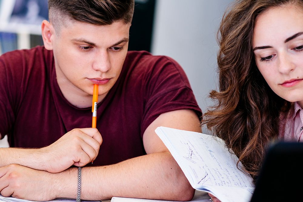 Aluno e aluna estudando juntos para simulado do ENEM.